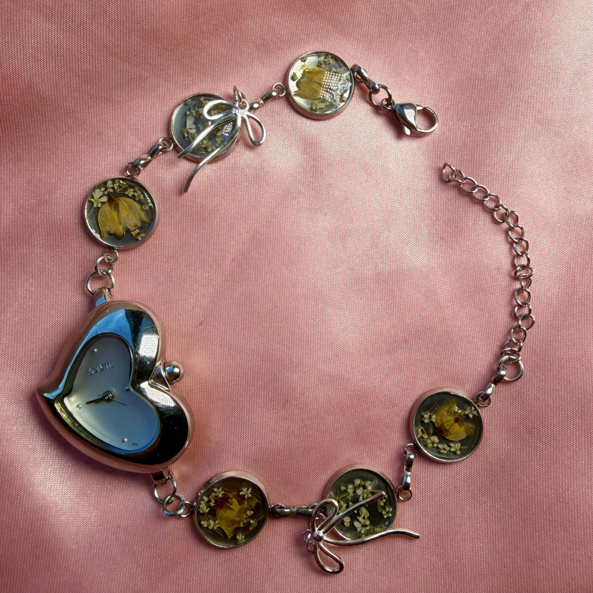 Close-up of silver-tone heart-shaped bracelet with a handmade floral band