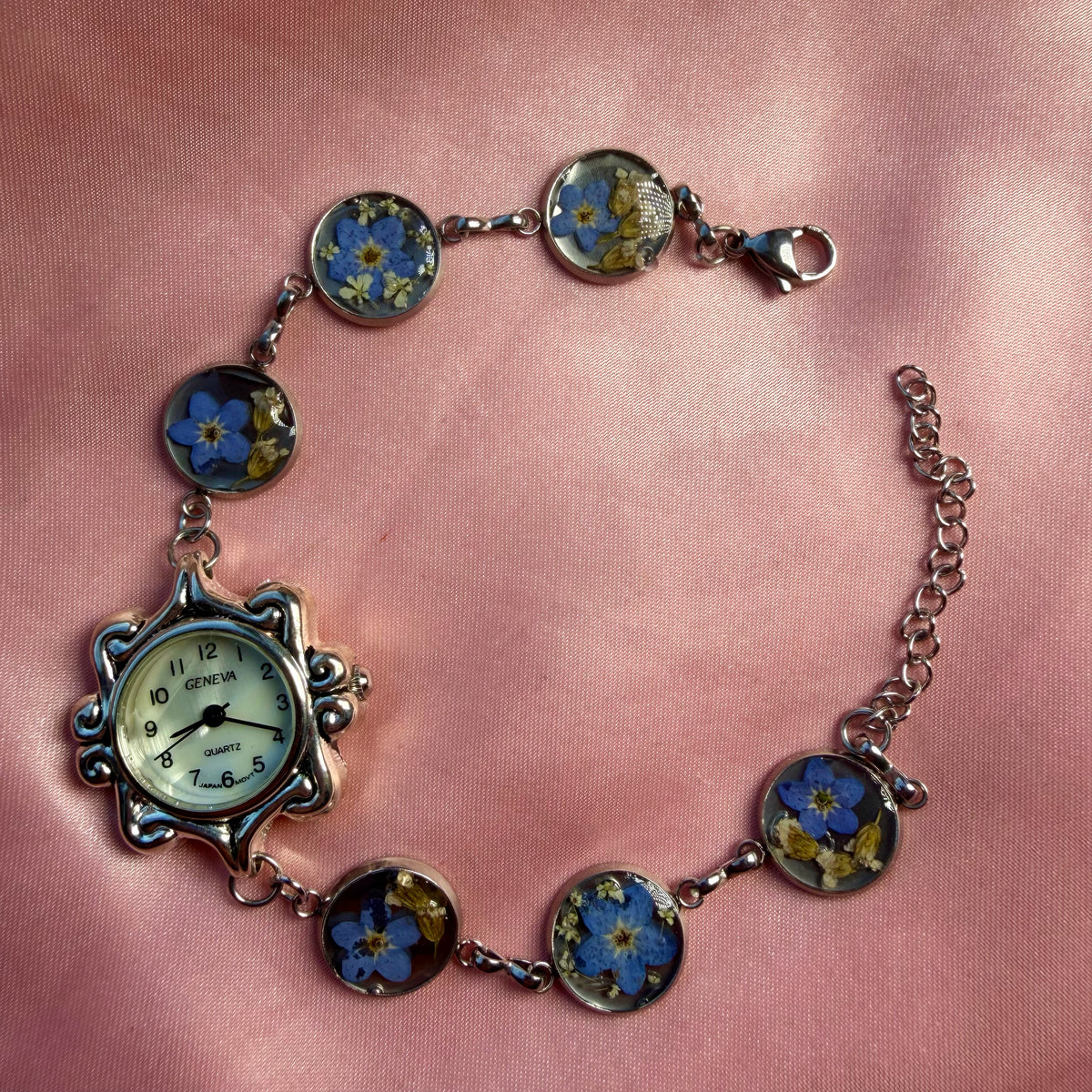 Close-up of silver-tone bracelet with an ornate oval face and a handmade floral band