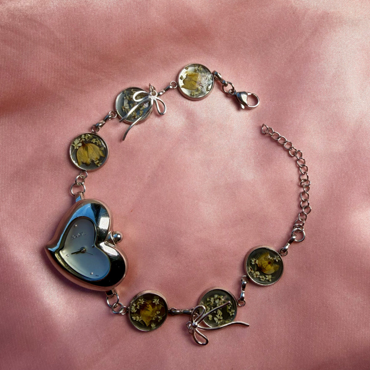 A silver-tone heart-shaped bracelet with a handmade floral band