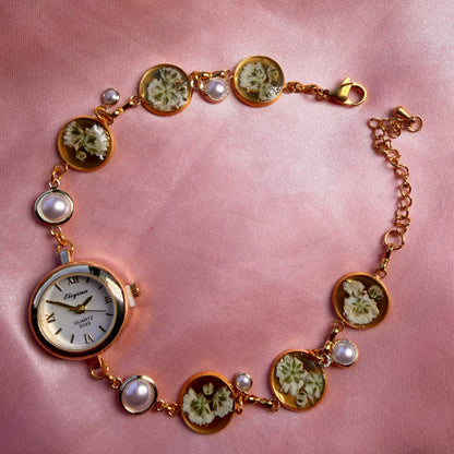 A gold-tone round bracelet with a pale dial and a handmade floral band