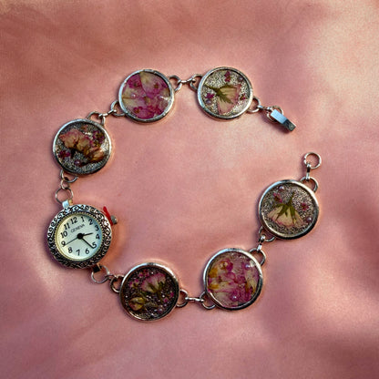 A silver-tone bracelet with an ornate round face and a handmade floral band