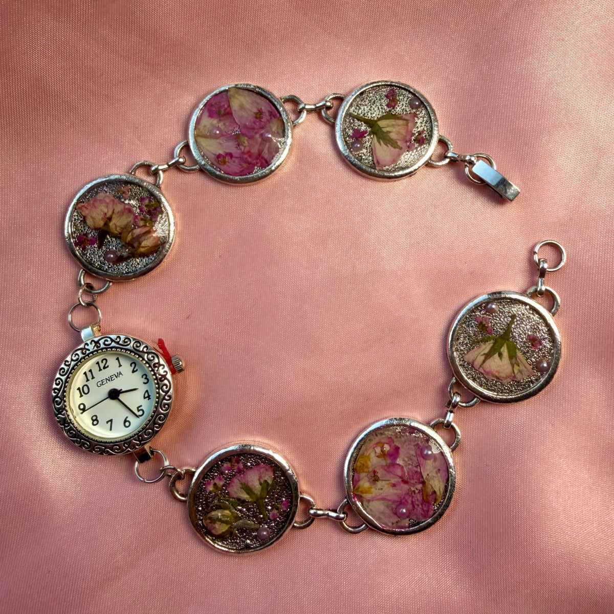 Close-up of silver-tone bracelet with an ornate round face and a handmade floral band